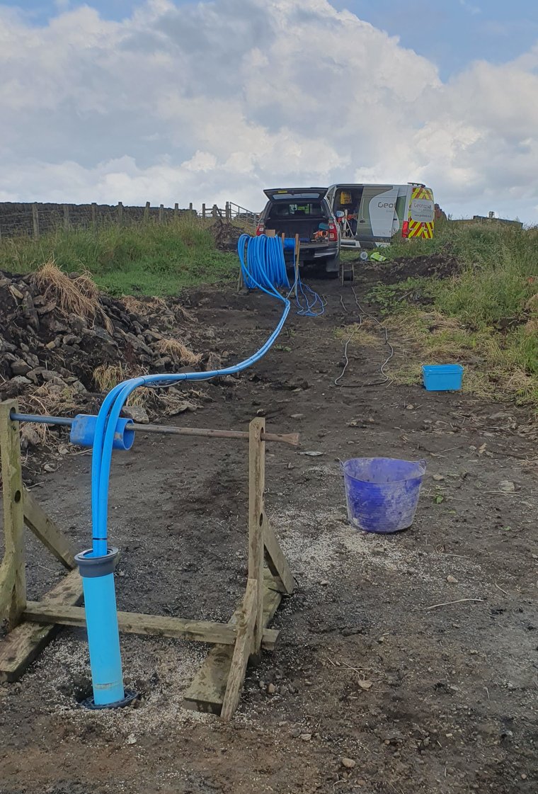 Completed Geotron water borehole wellhead on a moorland site with the support vehicle behind